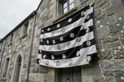 Drapeau breton Gwenn ha Du avec les onze hermines accroché sur une façade en granit breton