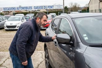 Homme examine une Nissan Qashqai d'occasion devant un concessionnaire